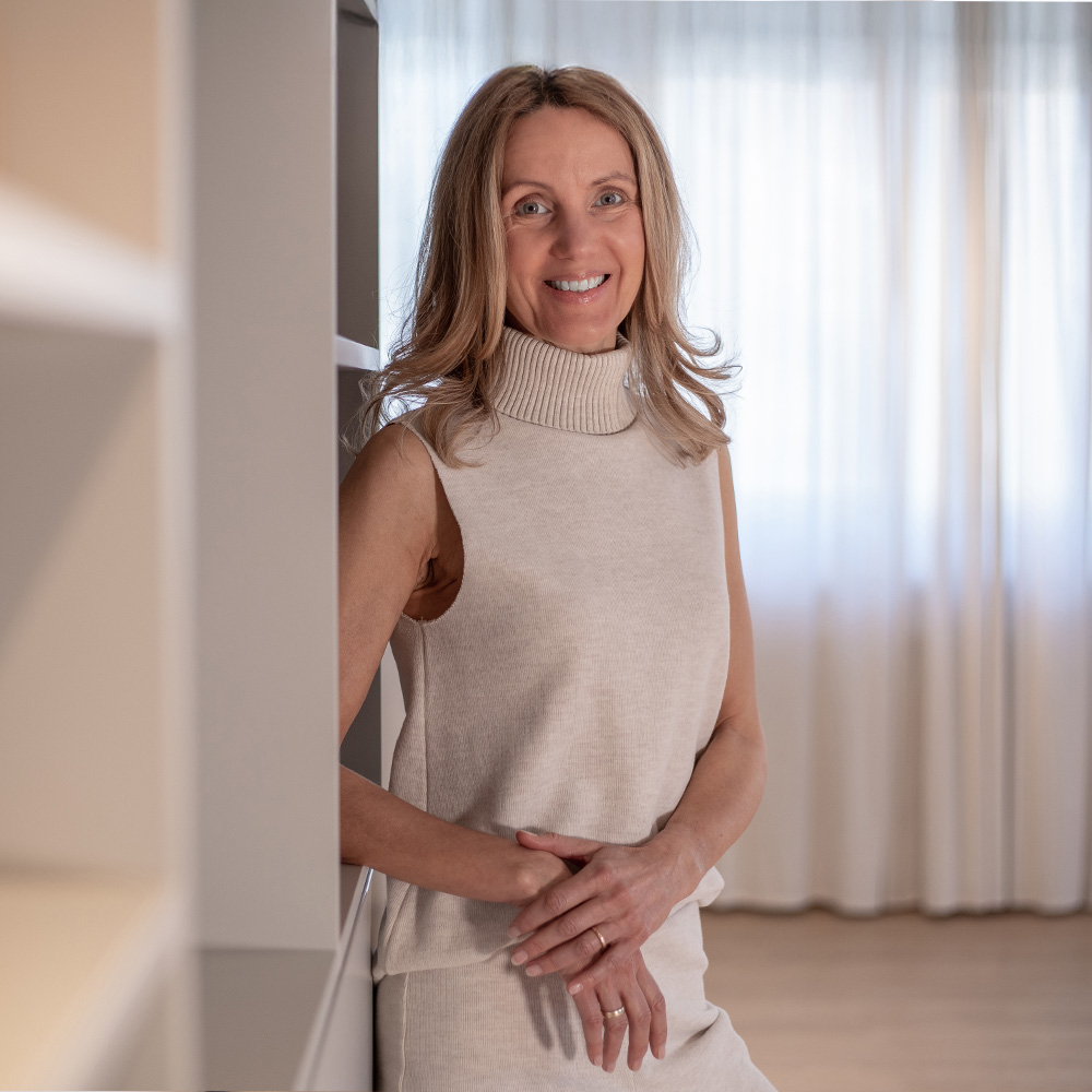Nicole Volkert lehnt am Regal und lächelt in die Kamera